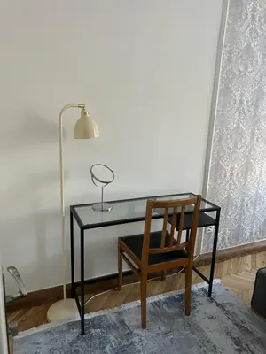 a glass desk with a chair and a lamp at City Park Apartment in Vilnius
