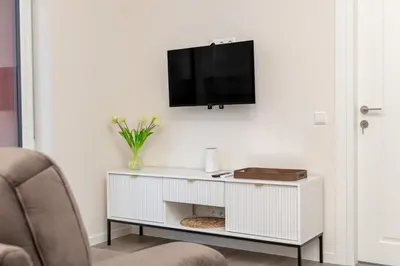 a white cabinet with a tv on a wall at Modern Apartment next to Kaunas Clinics in Kaunas