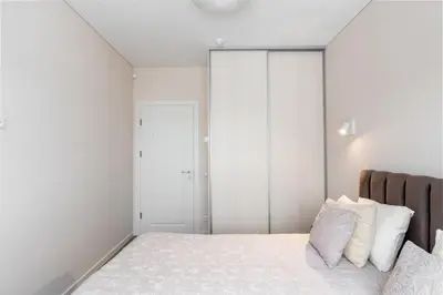 a bedroom with a bed with white walls and a closet at Modern Apartment next to Kaunas Clinics in Kaunas