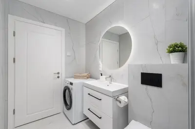 a white bathroom with a washing machine and a sink at Modern Apartment next to Kaunas Clinics in Kaunas