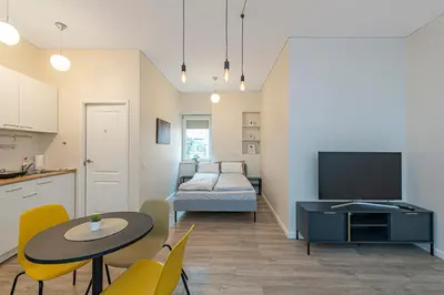 a living room with a table and a bedroom at Studio apartment Delight by Polo Apartments in Kaunas