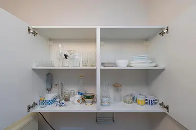 a white cabinet filled with glasses and dishes at Studio apartment Delight by Polo Apartments in Kaunas
