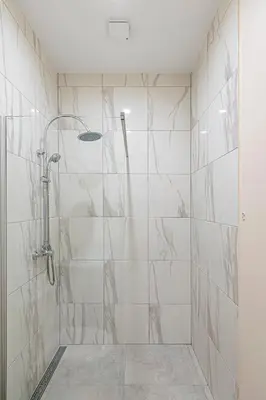 a bathroom with a shower with white tiles at Studio apartment Delight by Polo Apartments in Kaunas