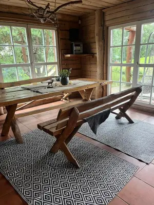 a wooden table and bench in a room with windows at Privatus namelis gamtoje greta Trakų in Daugirdiškės