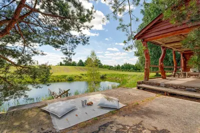 a wooden pavilion next to a lake with a table at Privatus namelis gamtoje greta Trakų in Daugirdiškės