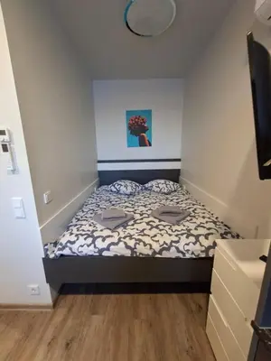 a small bedroom with a bed and a television at Uzupio justo namai in Kaunas