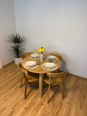 a wooden table with four chairs and a table and a plant at Urban Nest Čiurlionio Apartment City Center in Druskininkai