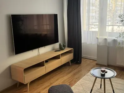 a living room with a large flat screen tv on a wall at Urban Nest Čiurlionio Apartment City Center in Druskininkai