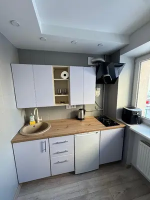 a kitchen with white cabinets and a sink at Urban Nest Čiurlionio Apartment City Center in Druskininkai