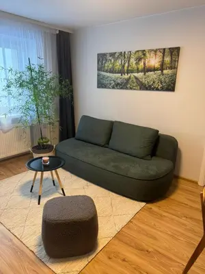 a living room with a green couch and a table at Urban Nest Čiurlionio Apartment City Center in Druskininkai