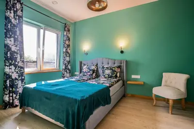 a bedroom with a bed and a chair and a window at River apartamentai in Pakopi