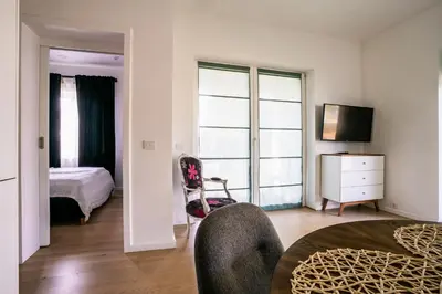 a room with a bedroom with a bed and a chair at River apartamentai in Pakopi