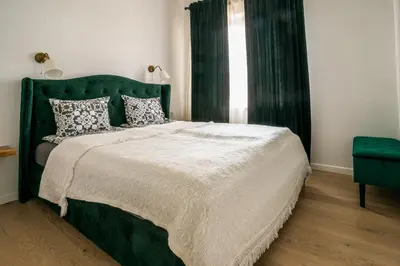a bedroom with a large bed with a green headboard at River apartamentai in Pakopi
