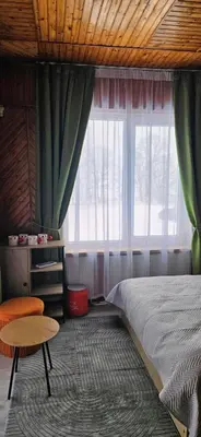 a bedroom with a bed and a table and a window at Skodupės švenčių ir poilsio namai in Pakopi