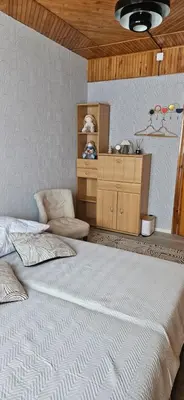 a bedroom with a large white bed and a wooden ceiling at Skodupės švenčių ir poilsio namai in Pakopi