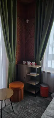 a room with green curtains and a stool and a table at Skodupės švenčių ir poilsio namai in Pakopi