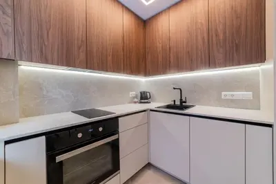 a kitchen with white counters and wooden cabinets at Sandal Apartments in Šiauliai