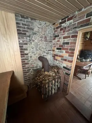a stone fireplace in a room with a brick wall at Sudervės pirtelė poilsiui gamtoje, Vilnius už 12 km in Sudervė