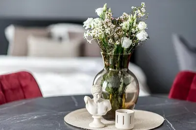 a vase with flowers and a cup on a table at Vilnius Studio Apartment with Free Parking and Self Check In in Vilnius