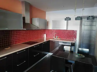 a kitchen with black cabinets and red tile at Vilnius Gate Skyline Studio in Vilnius