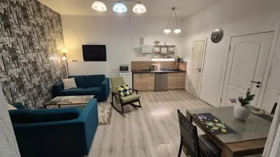 a living room with blue couches and a kitchen at Plytų Sienos Apartamentai in Kaunas