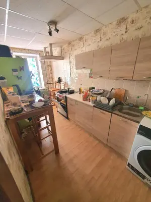 a kitchen with wooden cabinets and a wooden floor at Horses Forests Lakes Shops in Visaginas
