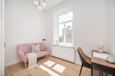 a living room with a pink chair and a table at Sunny Garden Street Apartment in Vilnius in Vilnius