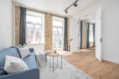 a living room with a blue couch and some windows at Sunny Garden Street Apartment in Vilnius in Vilnius