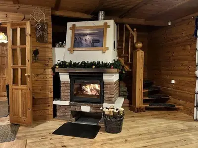 a living room with a fireplace in a log cabin at Gintarinė rasa in Inkartai