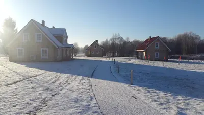 a house in the snow with houses in the background at Panemunio sodyba in Birštonas