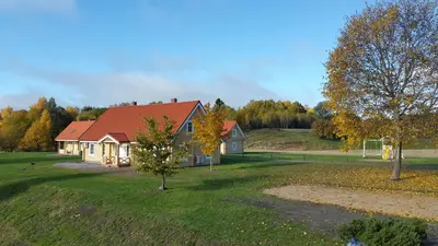 a house with a red roof on a green field at Panemunio sodyba in Birštonas