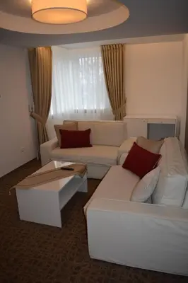 a living room with a white couch and red pillows at Mokomasis svetingumo centras in Utena