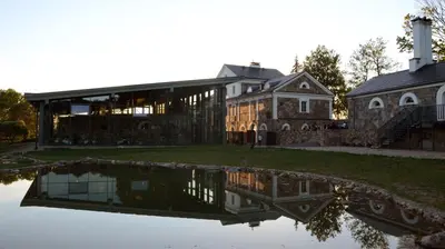 a house with a reflection in a body of water at Paliesiaus Dvaras in Mielagėnai