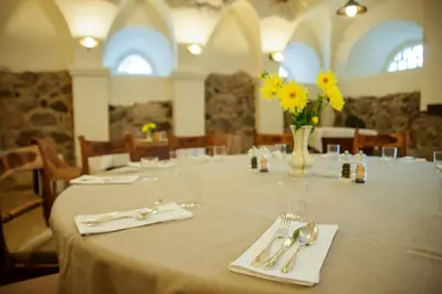 a table with silverware and a vase of yellow flowers at Paliesiaus Dvaras in Mielagėnai