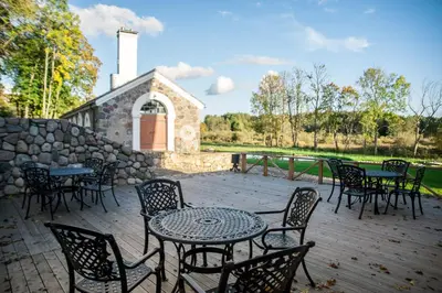 a patio with tables and chairs and a stone building at Paliesiaus Dvaras in Mielagėnai