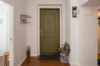 a hallway with a green door and a chair at Maironis Apartment in Kaunas