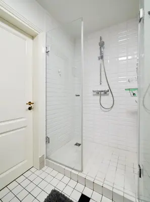 a white bathroom with a shower with a glass door at Town Hall Apartments FREE Parking in Vilnius