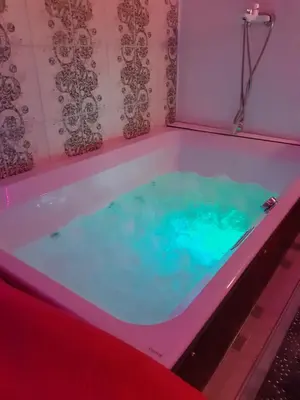 a hot tub in a room with a pink and blue at President Apartments in Vilnius