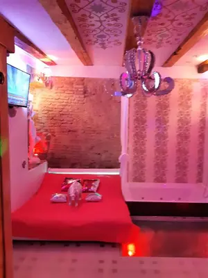 a cat sitting on a red bed in a room at President Apartments in Vilnius