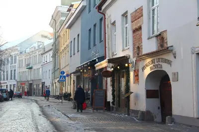 a person walking down a city street with buildings at German18-3A Luxury Vilnius apartment in Vilnius