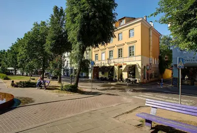 a person sitting on a bench in front of a yellow building at German18-3B Luxury Vilnius apartment in Vilnius