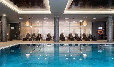 a swimming pool in a hotel lobby with chairs at UPA Medical SPA in Druskininkai