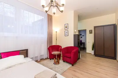 a bedroom with a bed and two red chairs at Apartamentai 555 in Vilnius