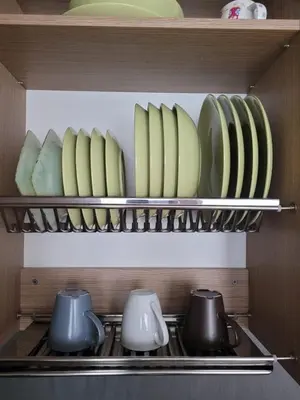 a kitchen shelf with plates and bowls and utensils at Saulės Sonata Etude in Druskininkai