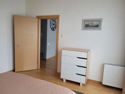 a bedroom with a dresser and a clock on the wall at Saulės Sonata Etude in Druskininkai