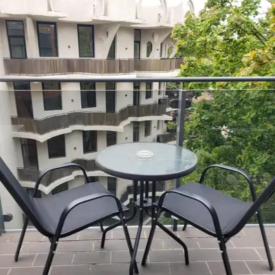 a table and chairs on a balcony with a building at Saulės Sonata Etude in Druskininkai