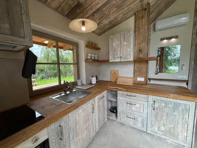 a large kitchen with wooden cabinets and a sink at Dabintos slėnis in Sumiliszki