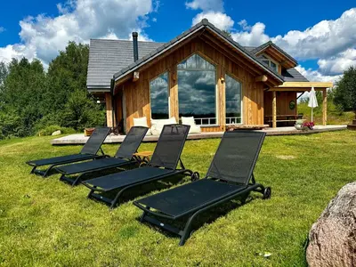 four lounge chairs sitting in the grass in front of a house at Dabintos slėnis in Sumiliszki