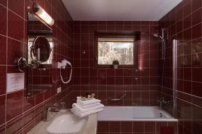 a red tiled bathroom with a tub and a sink at Pušynė in Birštonas