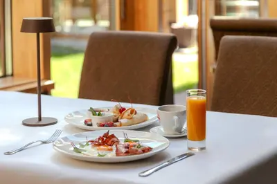 a table with two plates of food and a glass of orange juice at Pušynė in Birštonas